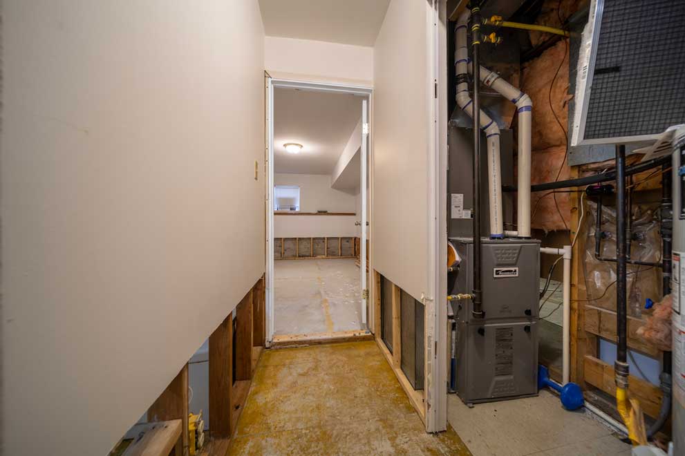 Basement mechanical room during the Lonsdale, North Vancouver home renovation, showing furnace, ductwork, and exposed framing.