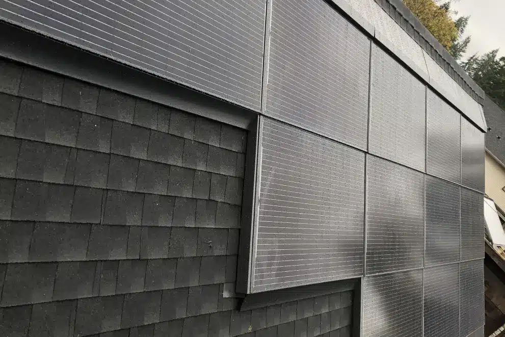 solar installation for small business VanClose-up view of black solar panels installed on a roof with dark shingles, aligned in a staggered pattern.couver - MJR Electric