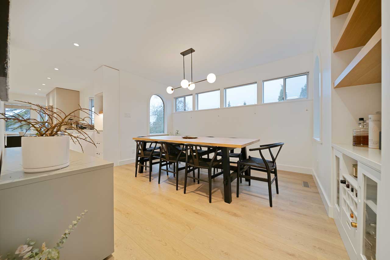 Dining room with a linear chandelier over the table and recessed pot lighting throughout