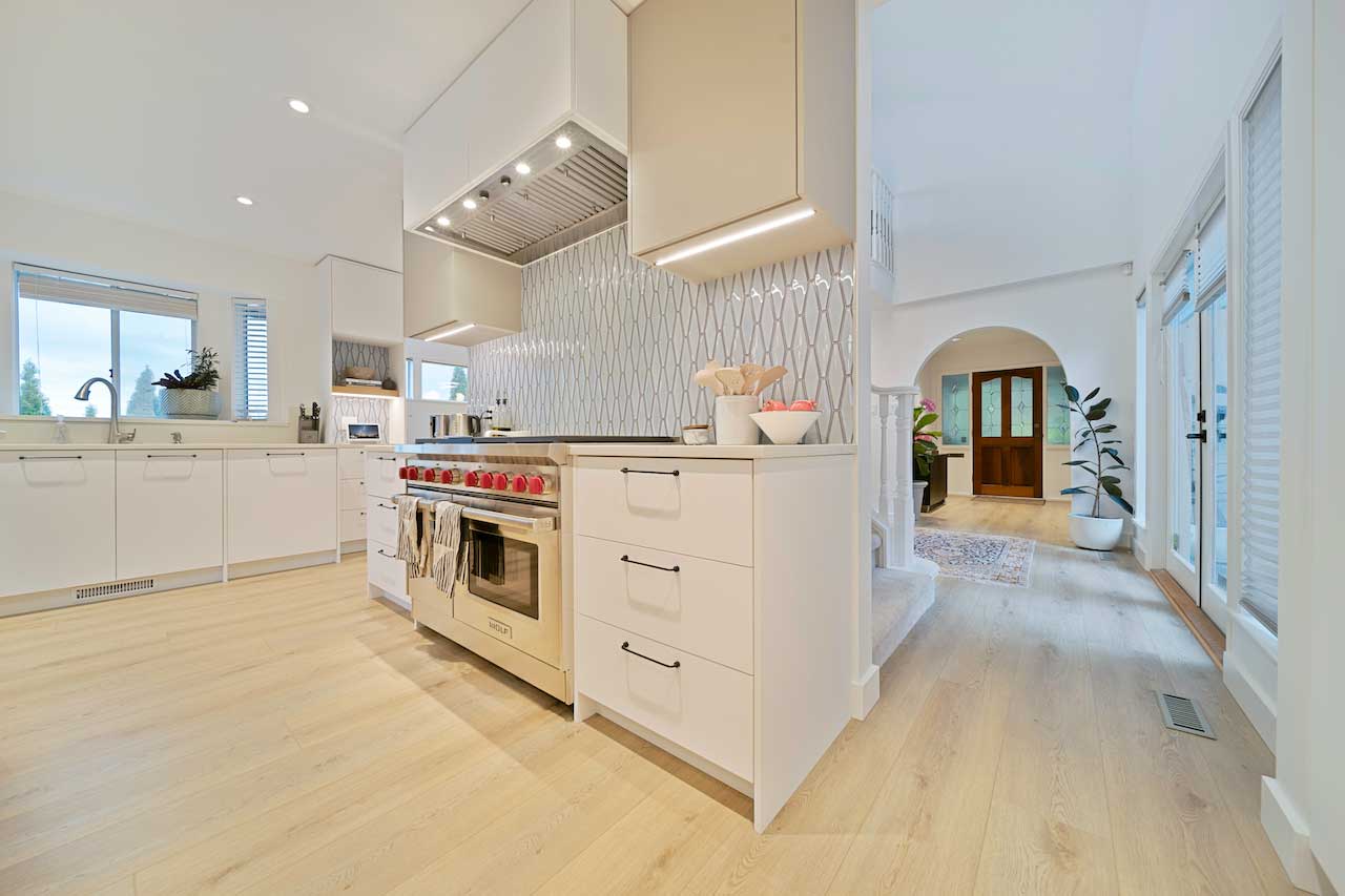 Kitchen with recessed pot lighting and under-hood lighting above a range, opening into an entry hallway