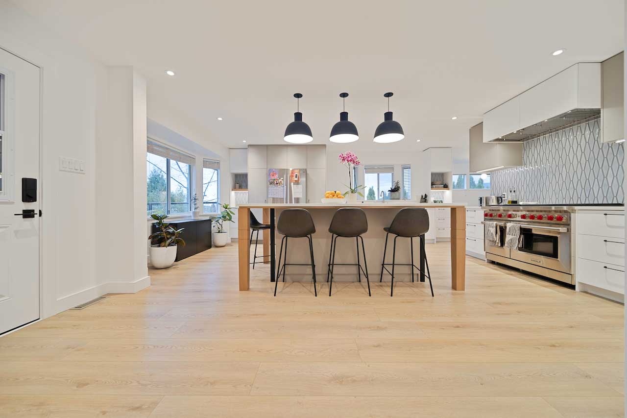Kitchen island with three matching pendant lights and recessed pot lighting throughout the space
