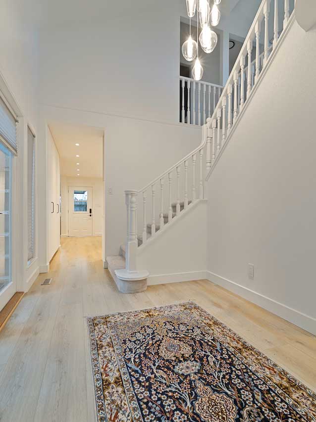 Cluster pendant chandelier over a staircase with recessed pot lighting